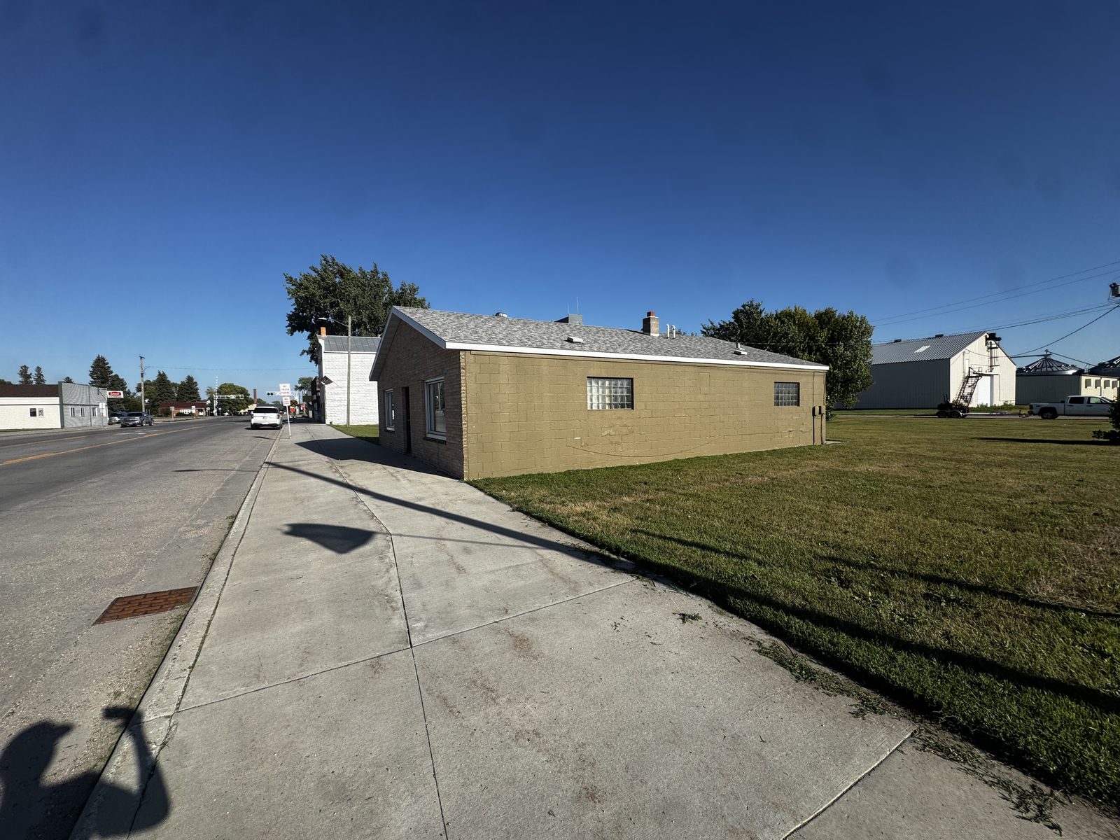 Front and side exterior of 116 W Broadway — painted concrete block building with glass-block windows on a sunny day in downtown Climax