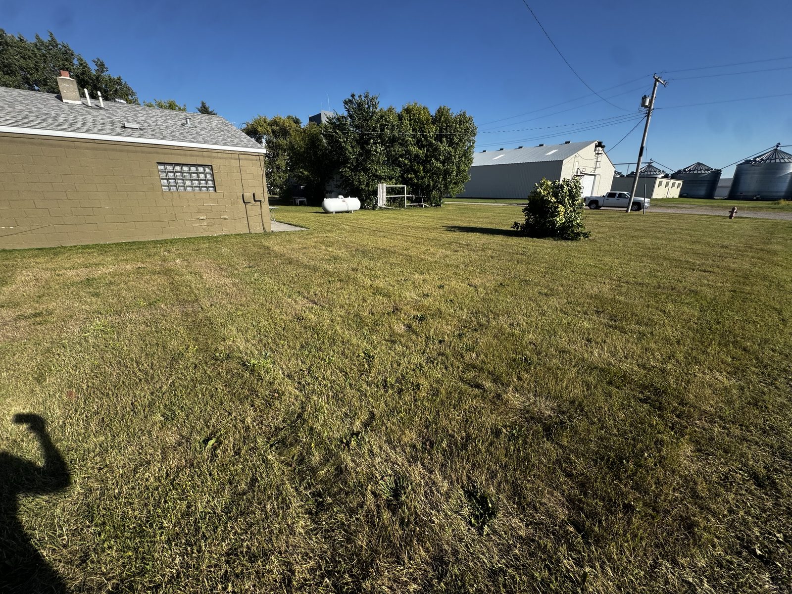 Rear of 116 W Broadway and its back yard, with propane tank and neighboring grain facilities in the background